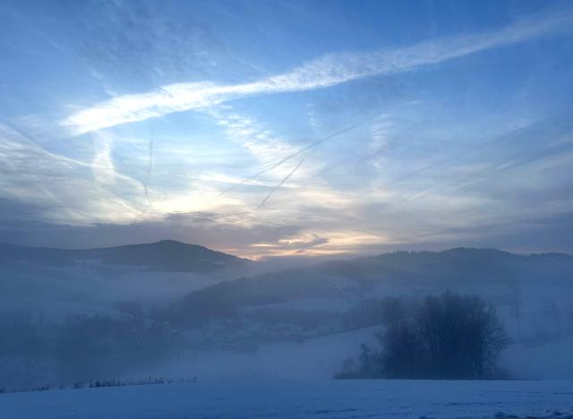 14 January 2026, Bavaria, Neukirchen: Sunshine and lingering fog can be seen over the winter landscape of Obermuehlbach, a district of Neukirchen. Photo: Ute Wessels/dpa