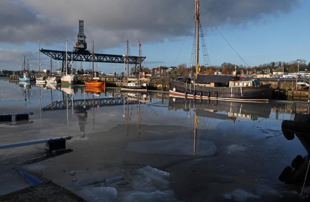14 January 2026, Mecklenburg-Western Pomerania, Rostock: Water covers the ice in the city harbor, reflecting the boats and the crane bridge. A thaw has melted the snow in the north. Photo: Bernd Wüstneck/dpa