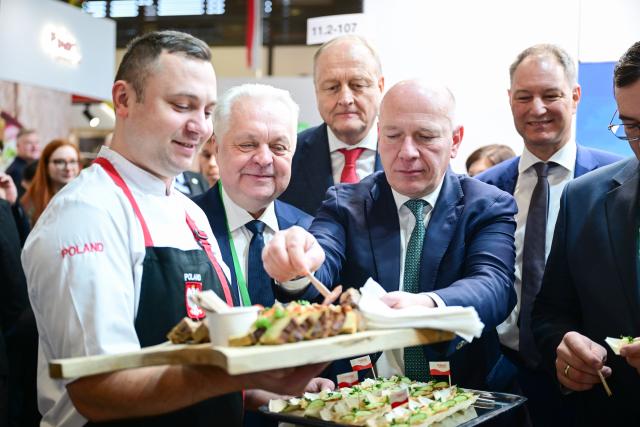 16 January 2026, Berlin: Kai Wegner, Governing Mayor of Berlin, tries a piece of sausage at the Polish stand during the opening tour at the start of the 90th International Green Week. Photo: Sebastian Christoph Gollnow/dpa