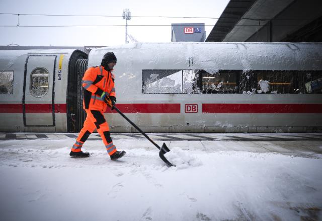 FILED - 09 January 2026, Hamburg: An employee pushes snow from a platform at the main station where a parked ICE train is parked. Deutsche Bahn has suspended long-distance services in northern Germany until at least midday due to the stormy winter weather. Photo: Christian Charisius/dpa