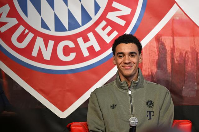 FILED - 04 January 2026, Bavaria, Simbach am Inn: Bayern Munich's Jamal Musiala sits on the podium during his visit to the FC Bayern fan club "Red Bulls Taubenbach". Jamal Musiala is set to return from a severe leg injury that sidelined him for half a year when Bundesliga leaders Bayern Munich visit RB Leipzig on Saturday. Photo: Uwe Lein/dpa