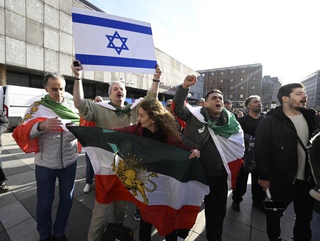17 January 2026, North Rhine-Westphalia, Cologne: Participants hold signs and flags during a demonstration in Cologne in support of the protests in Iran. Photo: Roberto Pfeil/dpa