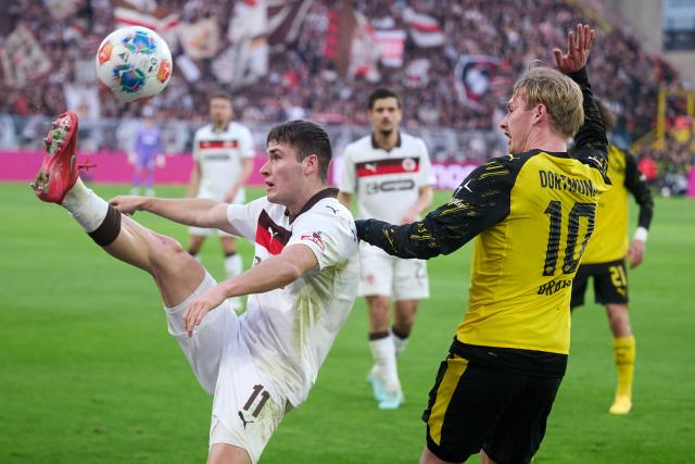 17 January 2026, North Rhine-Westphalia, Dortmund: Borussia Dortmund's Julian Brandt (R) and St. Pauli's Arkadiusz Pyrka in action during the German Bundesliga soccer match between Borussia Dortmund and FC St. Pauli at the Signal Iduna Park. Photo: Bernd Thissen/dpa - IMPORTANT NOTICE: DFL and DFB regulations prohibit any use of photographs as image sequences and/or quasi-video.