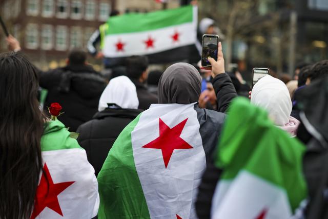 FILED - 10 December 2024, North Rhine-Westphalia, Duisburg: People wrapping themselves in Syrian flags gather in front of Duisburg Central Station. Photo: Christoph Reichwein/dpa