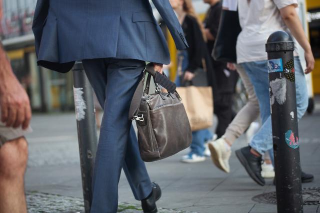FILED - 10 July 2023, Berlin: A man in a suit carries a leather briefcase in his hand. Photo: Fernando Gutierrez-Juarez/dpa