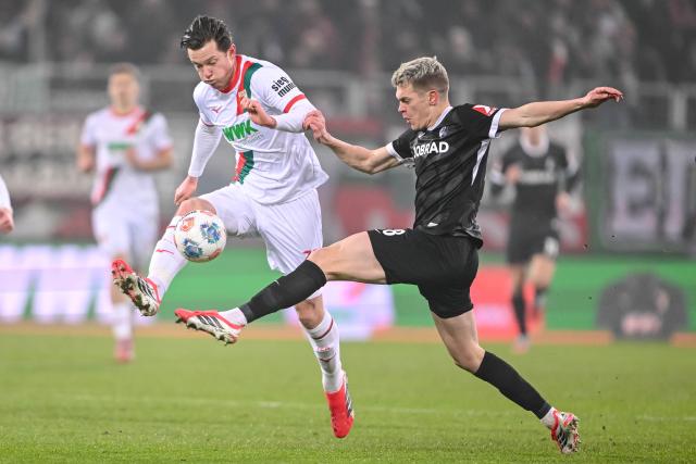 18 January 2026, Bavaria, Augsburg: Augsburg's Michael Gregoritsch (L) and Freiburg's Matthias Ginter battle for the ball during the German Bundesliga soccer match between FC Augsburg and SC Freiburg at WWK Arena. Photo: Harry Langer/dpa - WICHTIGER HINWEIS: Gemäß den Vorgaben der DFL Deutsche Fußball Liga bzw. des DFB Deutscher Fußball-Bund ist es untersagt, in dem Stadion und/oder vom Spiel angefertigte Fotoaufnahmen in Form von Sequenzbildern und/oder videoähnlichen Fotostrecken zu verwerten bzw. verwerten zu lassen.
