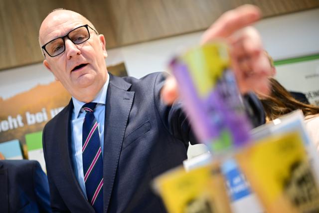 19 January 2026, Berlin: Dietmar Woidke, Minister President of Brandenburg, picks up an energy drink called Hell Wach at the Gläserne Molkerei stand during a tour of Brandenburg Day at the 90th International Green Week. The world's largest trade fair for food, agriculture and horticulture in Berlin is celebrating its 100th anniversary. Photo: Sebastian Christoph Gollnow/dpa