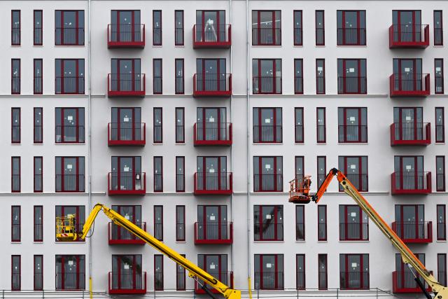 FILED - 14 January 2026, Berlin: Numerous balconies and windows can be seen on the façade of an apartment building under construction; two aerial work platforms are parked in front of the building. Photo: Jens Kalaene/dpa