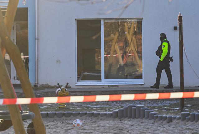 19 January 2026, Berlin: A police officer walks past a patio door lying on the ground in front of the daycare center in Niederschoeneweide, where a child dies in an accident. Photo: Britta Pedersen/dpa