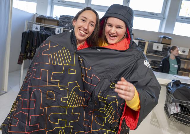19 January 2026, Bavaria, Munich: German alpine ski racers Kira Weidle-Winkelmann (L) and Emma Aicher share a rain poncho for fun during the clothing fitting for the Winter Games in Milan. Photo: Peter Kneffel/dpa