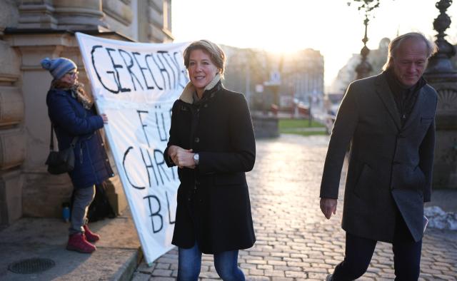20 January 2026, Hamburg: Christina Block (C), German restaurateur and entrepreneur, and her partner Gerhard Delling walk past demonstrators on their way to another day of hearings in the alleged child abduction trial at the Hamburg Regional Court. In a cloak-and-dagger operation on New Year's Eve 2023/24, two of Block's children were brought from Denmark to Germany. Photo: Marcus Brandt/dpa