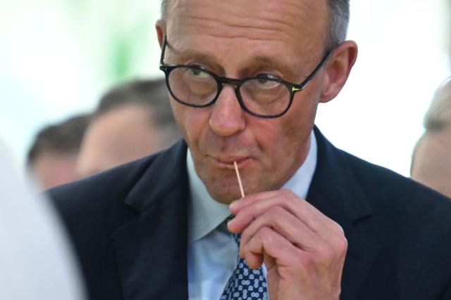 20 January 2026, Berlin: German Chancellor Friedrich Merz, eats during a tour of the 90th International Green Week. Photo: Britta Pedersen/dpa