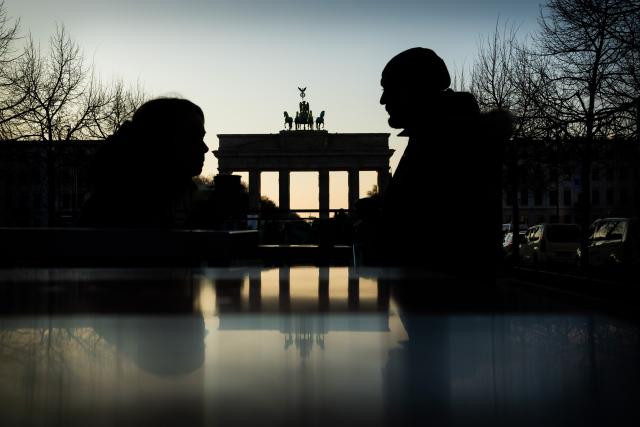 21 January 2026, Berlin: Nathalie and Abu stand in front of the Brandenburg Gate at stainless steel tables at a currywurst stand, with the scene reflected in them. Photo: Christoph Soeder/dpa
