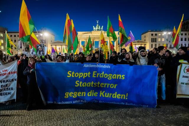 21 January 2026, Berlin: People stand with a banner says "Stop Erdogan's state terror against the Kurds!" in front of the Brandenburg Gate during a rally in solidarity with Rojava, the Kurdish autonomous region in northeastern Syria. Photo: Christoph Soeder/dpa
