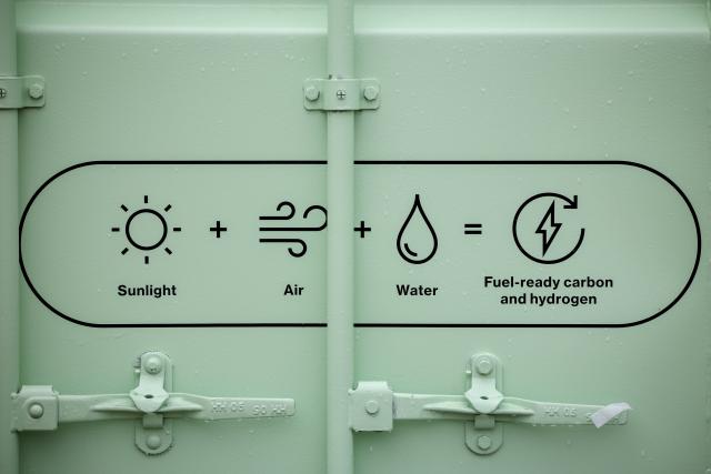 FILED - 20 November 2025, North Rhine-Westphalia, Duisburg: The pictograms "Sunlight + Air + Water = Fuel-ready carbon and hydrogen" can be seen on the new test facility, which can produce methane from green hydrogen and carbon dioxide from the air, at the Center for Fuel Cell Technology (ZBT). The system is marketed under the brand name "Liquid Solar". Photo: Christoph Reichwein/dpa