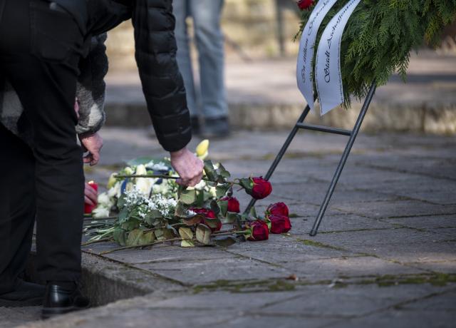 22 January 2026, Bavaria, Aschaffenburg: People lay flowers during a memorial ceremony for the victims of the knife attack in Schoental Park. One year ago a mentally ill man fatally attacked young children with a knife at the Park. Photo: Daniel Vogl/dpa