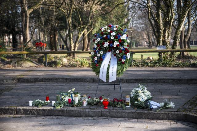 22 January 2026, Bavaria, Aschaffenburg: People lay flowers during a memorial ceremony for the victims of the knife attack in Schoental Park. One year ago a mentally ill man fatally attacked young children with a knife at the Park. Photo: Daniel Vogl/dpa