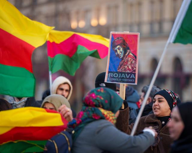22 January 2026, Berlin: A woman holds a poster reading "Rojava - A Symbol of Resistance" during a demonstration for the Kurdish region of Rojava in northern Syria at Pariser Platz Photo: Soeren Stache/dpa