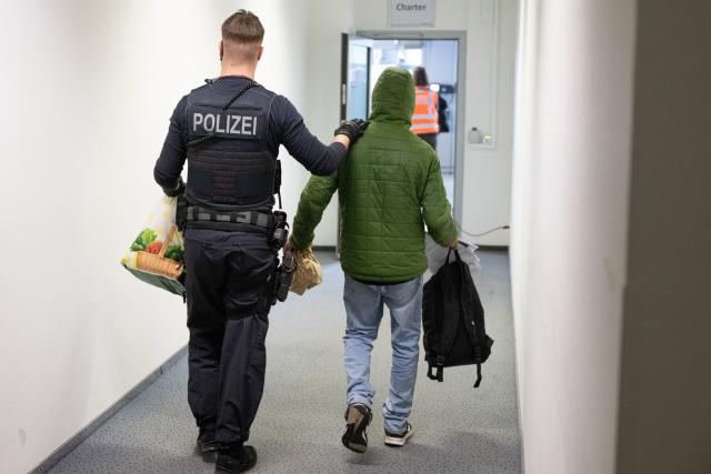 FILED - 25 February 2025, Hesse, Frankfurt/Main: A police officer escorts a man to a deportation flight to Pakistan. Germany deported 22,787 people over the course of 2025, up almost 14%, an Interior Ministry spokesman said on Thursday. Photo: Boris Roessler/dpa