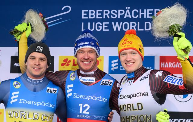 23 January 2026, Thuringia, Oberhof: (L-R) Austria's runner-up Jonas Mueller, Germany's winner Felix Loch and Germany's third-placed finisher Max Langenhan celebrate on the podium after the men's singles 2nd round competition at the Luge World Cup. Photo: Robert Michael/dpa