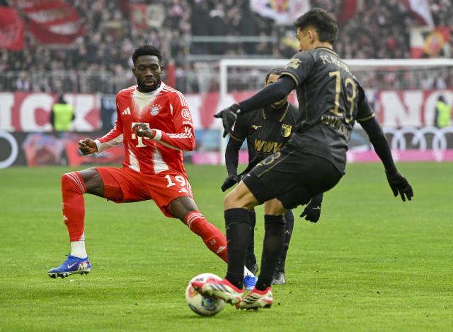 24 January 2026, Bavaria, Munich: Bayern Munich's Alphonso Davies (L) and Augsburg's Dimitris Giannoulis battle for the ball during the German Bundesliga soccer match between FC Bayern Munich and FC Augsburg at Allianz Arena. Photo: Peter Kneffel/dpa - WICHTIGER HINWEIS: Gemäß den Vorgaben der DFL Deutsche Fußball Liga bzw. des DFB Deutscher Fußball-Bund ist es untersagt, in dem Stadion und/oder vom Spiel angefertigte Fotoaufnahmen in Form von Sequenzbildern und/oder videoähnlichen Fotostrecken zu verwerten bzw. verwerten zu lassen.