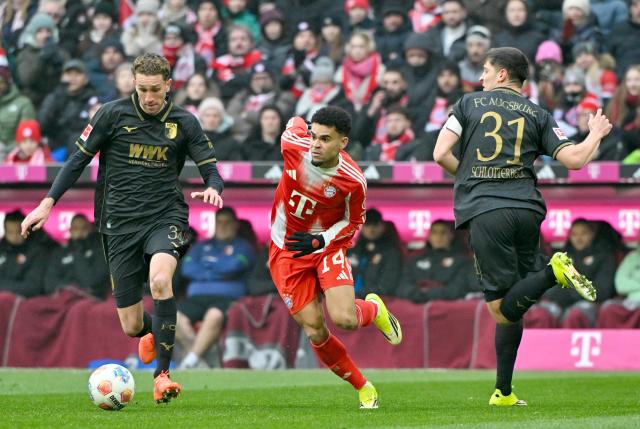 24 January 2026, Bavaria, Munich: Bayern Munich's Luis Diaz (C ) battles for the ball with Augsburg's Arthur Chaves and Keven Schlotterbeck during the German Bundesliga soccer match between FC Bayern Munich and FC Augsburg at Allianz Arena. Photo: Peter Kneffel/dpa - WICHTIGER HINWEIS: Gemäß den Vorgaben der DFL Deutsche Fußball Liga bzw. des DFB Deutscher Fußball-Bund ist es untersagt, in dem Stadion und/oder vom Spiel angefertigte Fotoaufnahmen in Form von Sequenzbildern und/oder videoähnlichen Fotostrecken zu verwerten bzw. verwerten zu lassen.