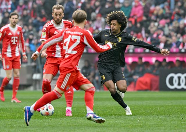 24 January 2026, Bavaria, Munich: Bayern Munich's Harry Kane and Lennart Karl (2nd R) battle for the ball with Augsburg's Han-Noah Massengo during the German Bundesliga soccer match between FC Bayern Munich and FC Augsburg at Allianz Arena. Photo: Peter Kneffel/dpa - WICHTIGER HINWEIS: Gemäß den Vorgaben der DFL Deutsche Fußball Liga bzw. des DFB Deutscher Fußball-Bund ist es untersagt, in dem Stadion und/oder vom Spiel angefertigte Fotoaufnahmen in Form von Sequenzbildern und/oder videoähnlichen Fotostrecken zu verwerten bzw. verwerten zu lassen.