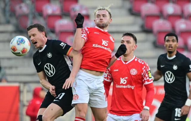 24 January 2026, Rhineland-Palatinate, Mainz: Mainz's Benedict Hollerbach (C) and Wolfsburg's Yannick Gerhardt (L) battle for the ball during the German Bundesliga soccer match between FSV Mainz 05 and VfL Wolfsburg at Mewa Arena. Photo: Torsten Silz/dpa - WICHTIGER HINWEIS: Gemäß den Vorgaben der DFL Deutsche Fußball Liga bzw. des DFB Deutscher Fußball-Bund ist es untersagt, in dem Stadion und/oder vom Spiel angefertigte Fotoaufnahmen in Form von Sequenzbildern und/oder videoähnlichen Fotostrecken zu verwerten bzw. verwerten zu lassen.