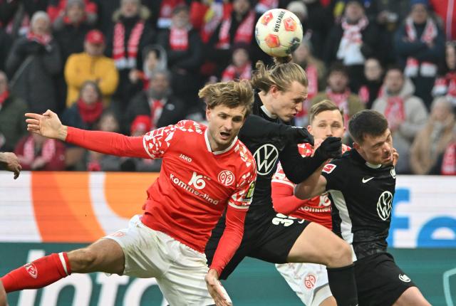24 January 2026, Rhineland-Palatinate, Mainz: Mainz's Stefan Posch (L) and Patrick Wimmer (C) battle for the ball during the German Bundesliga soccer match between FSV Mainz 05 and VfL Wolfsburg at Mewa Arena. Photo: Torsten Silz/dpa - WICHTIGER HINWEIS: Gemäß den Vorgaben der DFL Deutsche Fußball Liga bzw. des DFB Deutscher Fußball-Bund ist es untersagt, in dem Stadion und/oder vom Spiel angefertigte Fotoaufnahmen in Form von Sequenzbildern und/oder videoähnlichen Fotostrecken zu verwerten bzw. verwerten zu lassen.