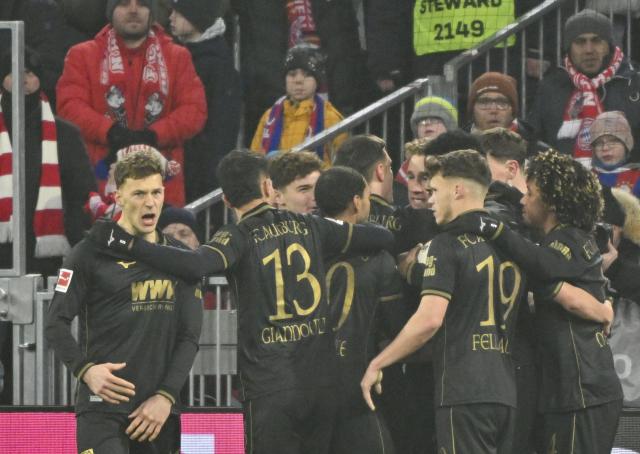 24 January 2026, Bavaria, Munich: Augsburg players celebrate their side's first goal during the German Bundesliga soccer match between FC Bayern Munich and FC Augsburg at Allianz Arena. Photo: Peter Kneffel/dpa - WICHTIGER HINWEIS: Gemäß den Vorgaben der DFL Deutsche Fußball Liga bzw. des DFB Deutscher Fußball-Bund ist es untersagt, in dem Stadion und/oder vom Spiel angefertigte Fotoaufnahmen in Form von Sequenzbildern und/oder videoähnlichen Fotostrecken zu verwerten bzw. verwerten zu lassen.