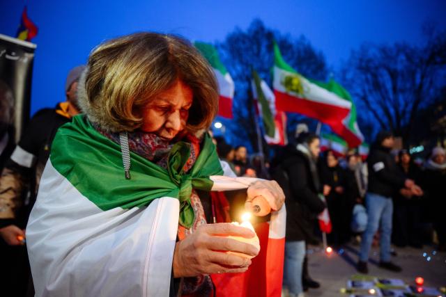 24 January 2026, Hamburg: A woman lights a candle during a protest at the Binnenalster against the Iranian government and religious leaders and in solidarity with the recent protests in the Islamic country. Photo: Gregor Fischer/dpa