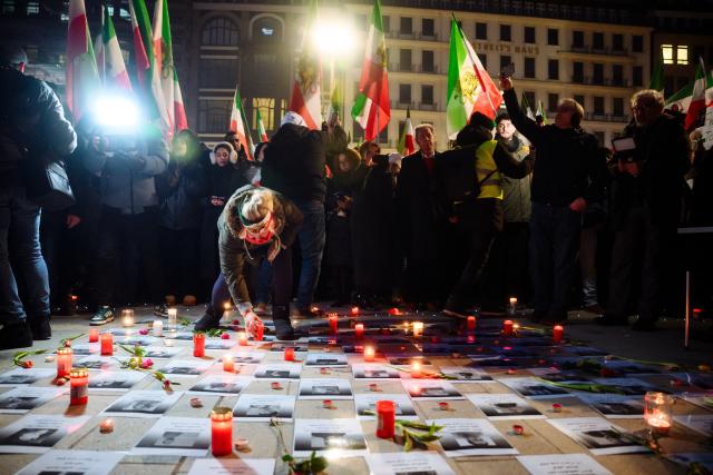 24 January 2026, Hamburg: People places a candle next to printed portraits of killed civilians in a protest at the Binnenalster against the Iranian government and religious leaders and in solidarity with the recent protests in the Islamic country. Photo: Gregor Fischer/dpa