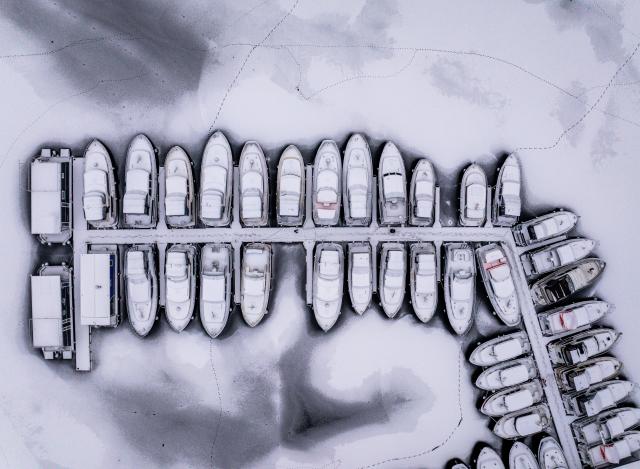 27 January 2026, Mecklenburg-Western Pomerania, Waren (Müritz): An aerial view  taken with a drone shows houseboats and charter boats lie in the ice in the harbor at Fischerhof Eldenburg in the Mecklenburg Lake District. The frosty weather of the past few days has left the lakes and canals partially covered in ice. Photo: Jens Büttner/dpa