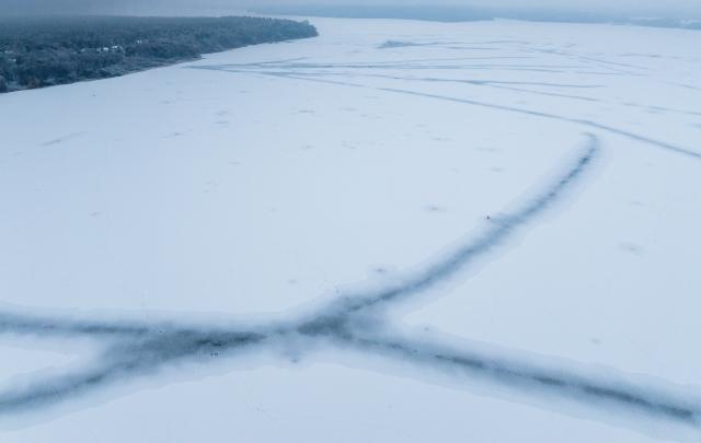 27 January 2026, Mecklenburg-Western Pomerania, Waren (Mueritz): An aerial view shows the Mueritz Lake completely covered in ice in front of the harbor. According to the Water and Shipping Authority, the entire surface of Germany's largest inland lake is covered in a thick layer of ice for the first time in years due to the persistent frosty weather. Photo: Jens Büttner/dpa
