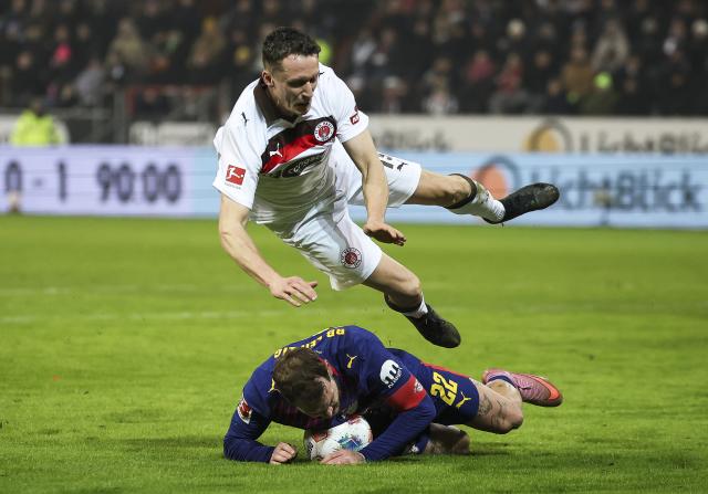 27 January 2026, Hamburg: Leipzig's David Raum fouls Pauli's Martijn Kaars during the German Bundesliga soccer match between FC St. Pauli and RB Leipzig at the Millerntor-Stadion. Photo: Christian Charisius/dpa - IMPORTANT NOTICE: DFL and DFB regulations prohibit any use of photographs as image sequences and/or quasi-video.