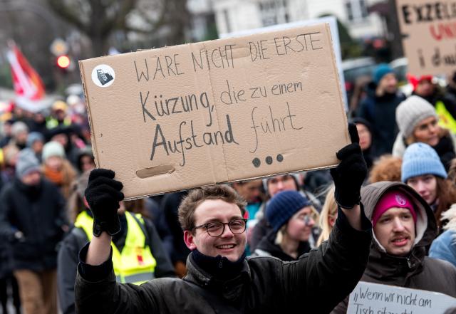 28 January 2026, Hamburg: Participants in a warning strike by academic staff and student employees march through the city center during a demonstration, holding a sign reading "Wouldn't be the first cut that leads to an uprising". In the current collective bargaining round of the federal states (TV-L), the trade unions are calling for action at over 60 university locations. Photo: Daniel Bockwoldt/dpa
