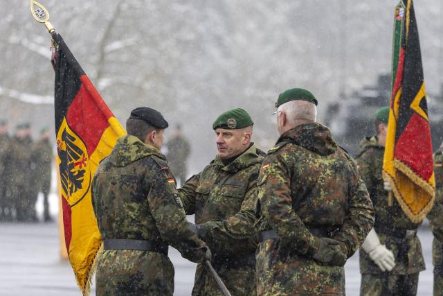 29 January 2026, Bavaria, Veitshoechheim: Brigadier General Christoph Huber (C), commander of Panzer brigade 45, hands over the flag of Panzer bataillon 203 to Lieutenant Colonel Oliver Kaufmann, commander of Panzer bataillon 203, at the roll call for the subordination of Panzergrenadier bataillon 122 and Panzer bataillon 203 to Panzer brigade 45 "Lithuania". Photo: Heiko Becker/dpa