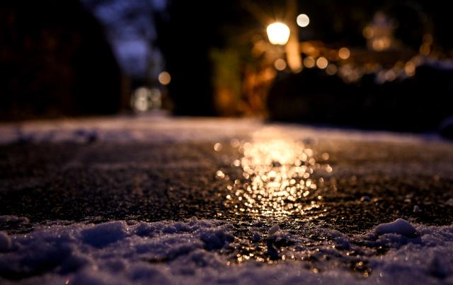 30 January 2026, Berlin: An icy sidewalk glistens in the light of a lantern. Photo: Britta Pedersen/dpa