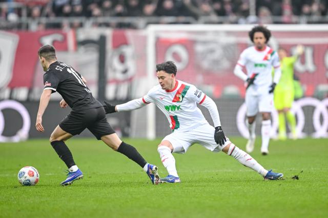 31 January 2026, Bavaria, Augsburg: St. Pauli's Arkadiusz Pyrka (L) in action against Augsburg's Fabian Rieder during the German Bundesliga soccer match between FC Augsburg and FC St. Pauli at the WWK Arena. Photo: Harry Langer/dpa - IMPORTANT NOTICE: DFL and DFB regulations prohibit any use of photographs as image sequences and/or quasi-video.
