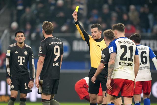 31 January 2026, Hamburg: Referee Harm Osmers (C) shows Bayern Munich's Harry Kane the yellow cardduring the German Bundesliga soccer match between Hamburger SV and FC Bayern Munich at the Volksparkstadion Photo: Marcus Brandt/dpa - IMPORTANT NOTICE: DFL and DFB regulations prohibit any use of photographs as image sequences and/or quasi-video.