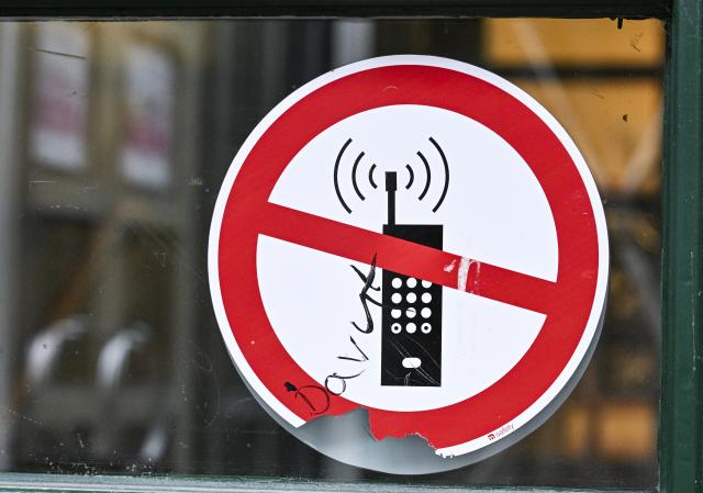 FILED - 12 December 2024, Berlin: A sign with a crossed-out cell phone symbol indicates the ban on cell phones in a school. Photo: Jens Kalaene/dpa