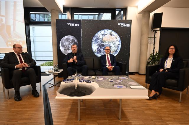04 February 2026, Bavaria, Wessling: (L-R) Markus Moeller, member of the OHB Management Board, Markus Soeder, Minister President of Bavaria, Josef Aschbacher, ESA Director General, and Chiara Pedersoli, OHB Systems CEO, sit in front of a model of a possible moon landing station at the OHB space company as part of the "MoonTalk" on the founding of the "European Moonport Company" for the development of high technologies for the moon. Photo: Felix Hörhager/dpa
