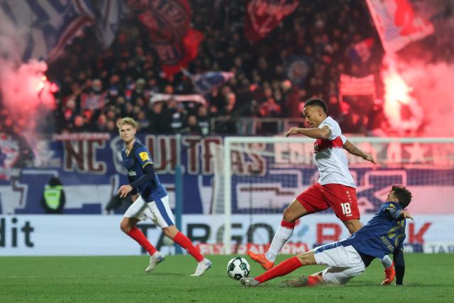 04 February 2026, Schleswig-Holstein, Kiel: Stuttgart's Jamie Leweling and Holstein Kiel's Jonas Meffert (R) battle for the ball during the German DFB Cup quarterfinal soccer match between Holstein Kiel and VfB Stuttgart at Holstein Stadium. Photo: Christian Charisius/dpa - IMPORTANT NOTICE: DFL and DFB regulations prohibit any use of photographs as image sequences and/or quasi-video.