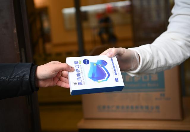 FILED - 24 January 2022, Berlin: An employee hands over a package of FFP2 masks to a young woman during a distribution campaign of free FFP2 masks for people in need at Neukoelln City Hall. Photo: Britta Pedersen/dpa-Zentralbild/dpa