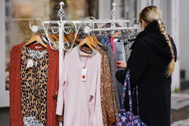 FILED - 15 March 2021, Rhineland-Palatinate, Pirmasens: A customer stands at a clothes Rack in front of a shop in the pedestrian zone. The European Union is to ban certain companies from destroying unsold clothes, clothing accessories and shoes in an effort to cut textile waste. Photo: Uwe Anspach/dpa
