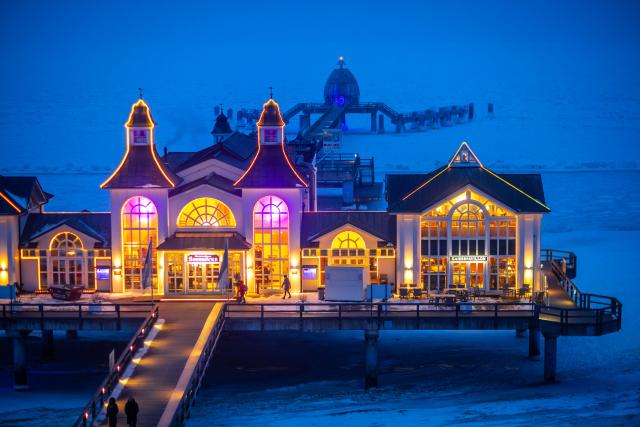 10 February 2026, Mecklenburg-Western Pomerania, Sellin: The pier on the Baltic Sea coast on the island of Ruegen surrounded by a closed ice cover is illuminated. Photo: Jens Büttner/dpa
