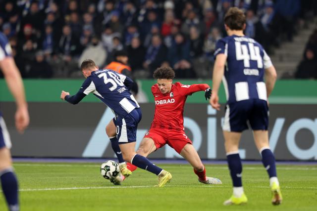 10 February 2026, Berlin: Freiburg's Derry Scherhant (C) and Hertha's Paul Seguin battle for the ball during the German DFB Cup quarter-final soccer match between Hertha BSC and SC Frei
burg at Olympiastadion. Photo: Andreas Gora/dpa