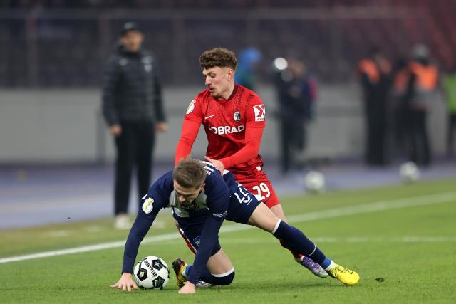 10 February 2026, Berlin: Freiburg's Philipp Treu and Hertha's Marten Winkler (L) battle for the ball during the German DFB Cup quarter-final soccer match between Hertha BSC and SC Frei
burg at Olympiastadion. Photo: Andreas Gora/dpa