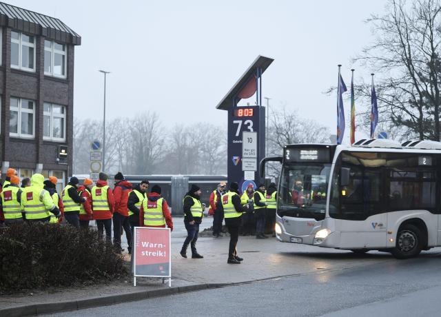 11 February 2026, Hamburg: Employees of Verkehrsbetriebe Hamburg-Holstein (VHH) stand in front of the entrance to the Schenefeld depot during a warning strike. The unions are demanding a binding offer from the employer for the third round of collective bargaining in the public sector of the federal states, which begins on Wednesday, with higher wages and shorter terms than previously promised. Photo: Christian Charisius/dpa