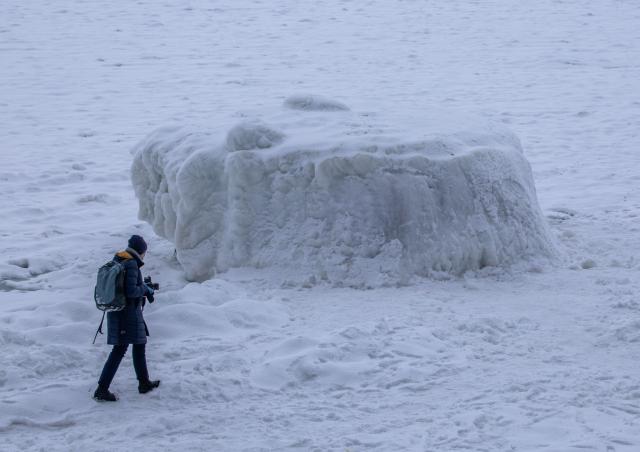 11 February 2026, Mecklenburg-Western Pomerania, Sassnitz: A photographer walks across the ice of the Baltic Sea off the coast, passing a large block of ice. Photo: Jens Büttner/dpa